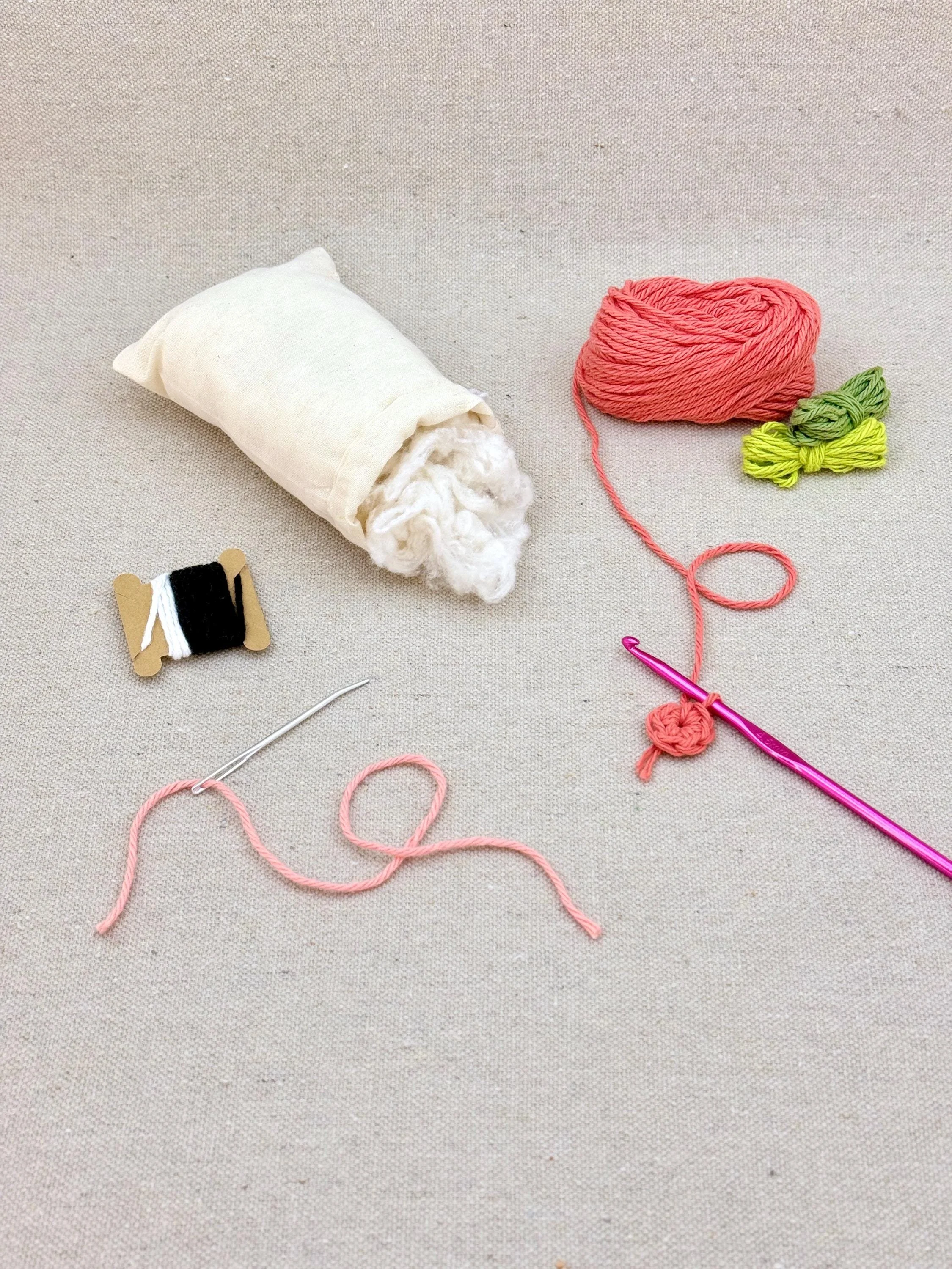 A coral amigurumi peach mid project using a DIY crochet kit