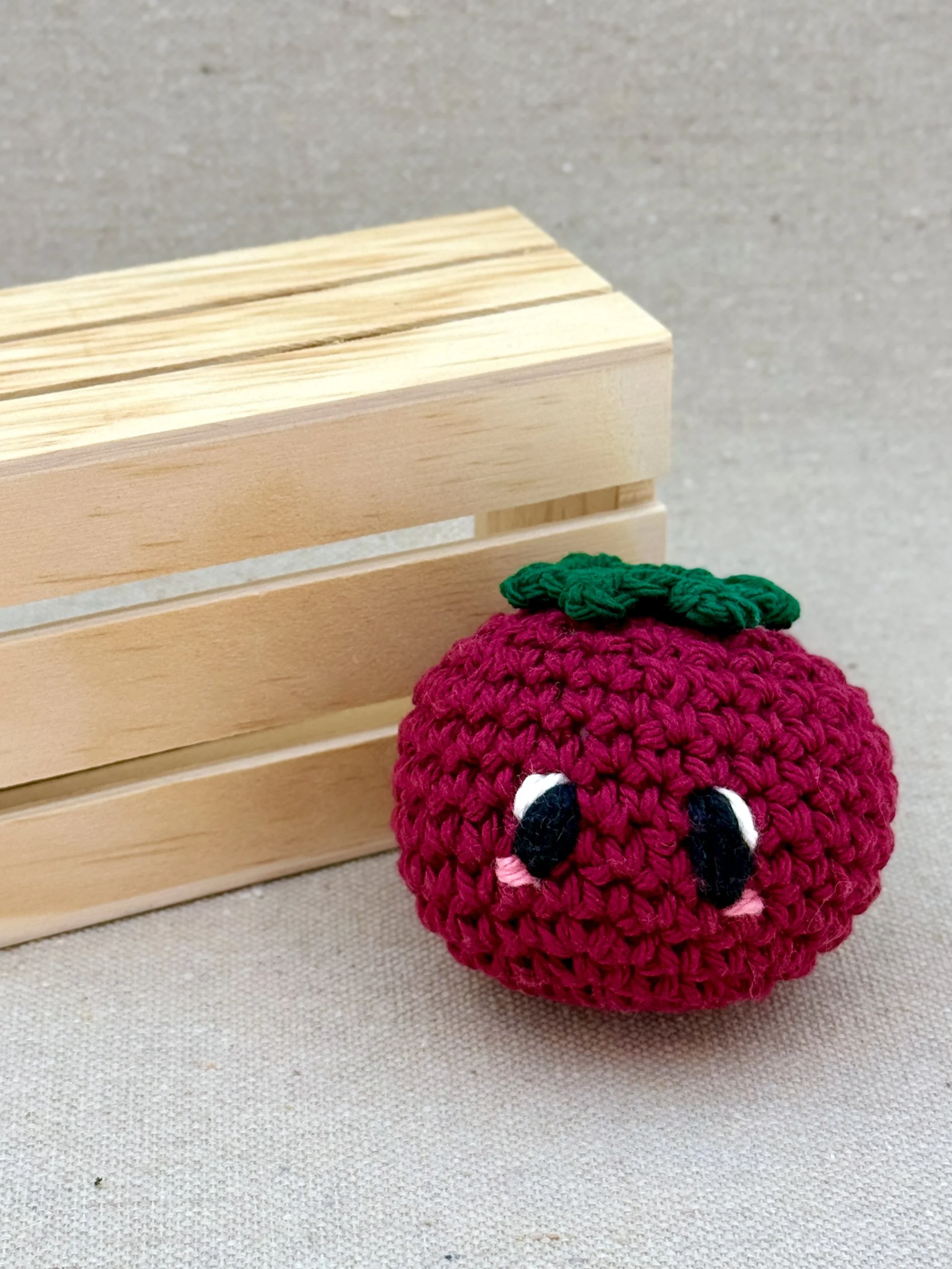 A burgundy amigurumi tomato plush posed with a mini wooden crate (Copy)