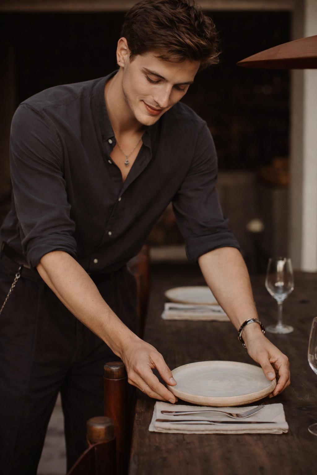 Man in een zwart overhemd die een lege dienblad op een eettafel zet in een restaurant.