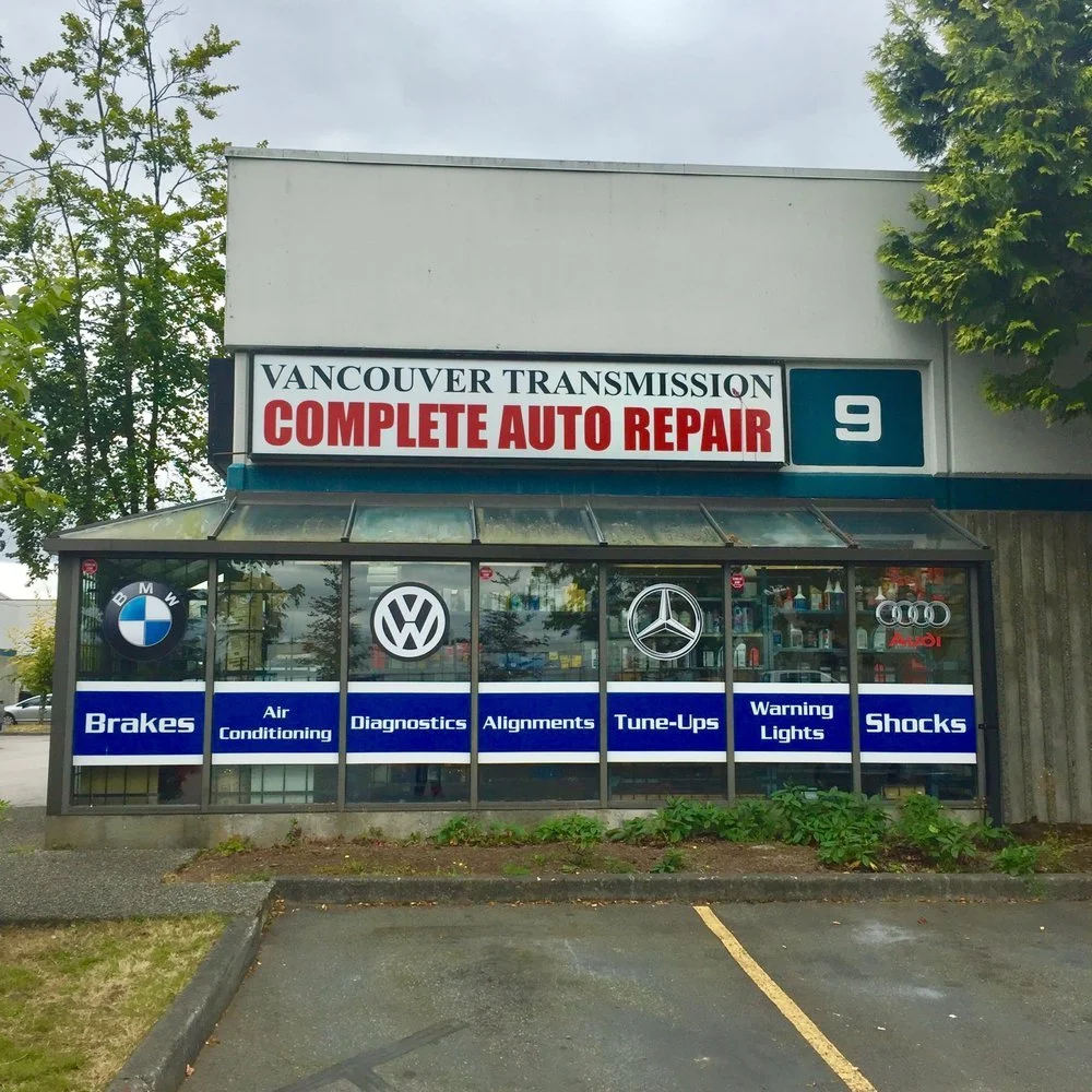 Auto repair shop with signs for BMW, Volkswagen, Mercedes-Benz, and Audi services, including brakes, air conditioning, diagnostics, alignments, tune-ups, warning lights, shocks, and more.
