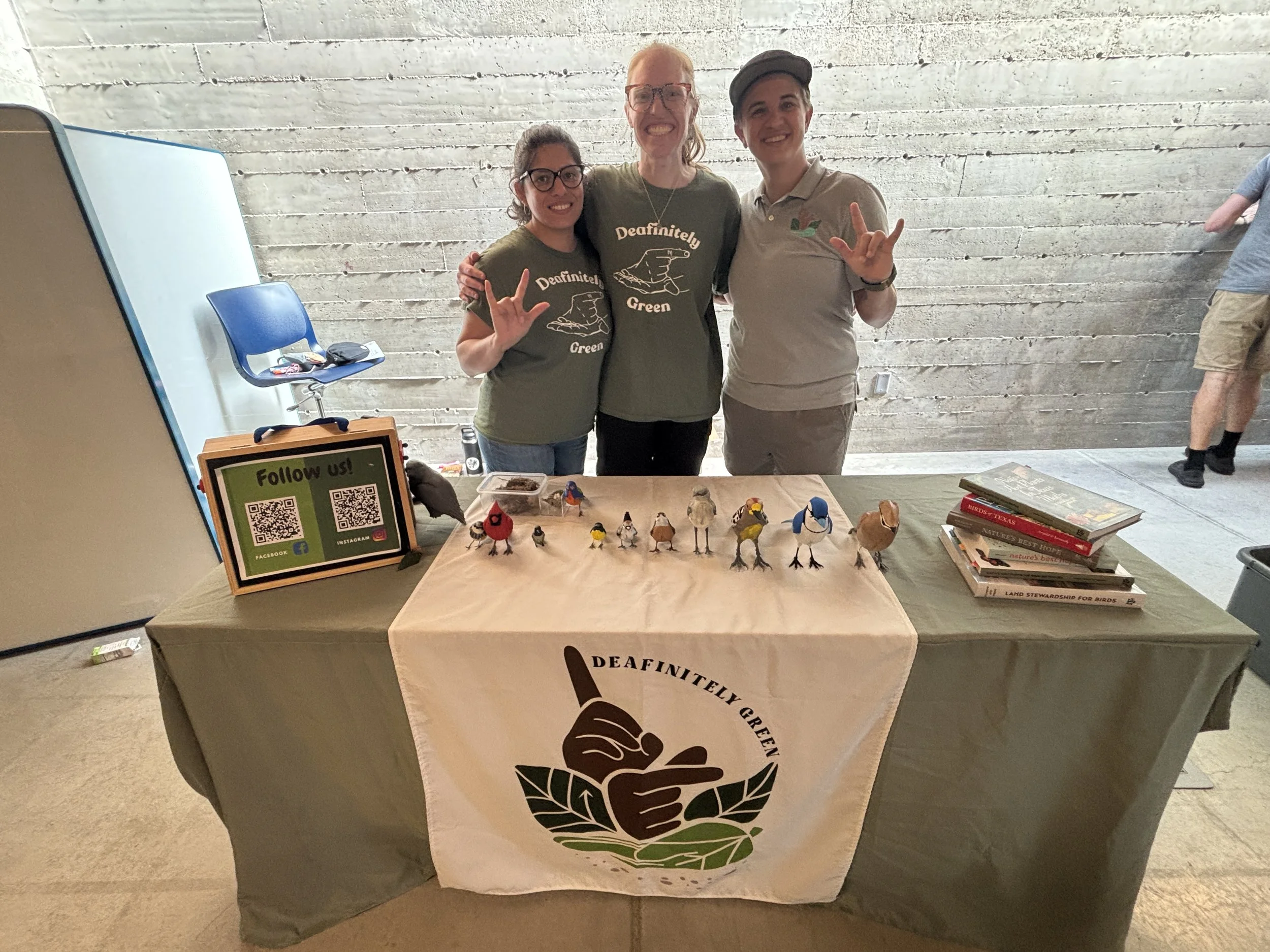 Three women standing behind a table with the DG! logo