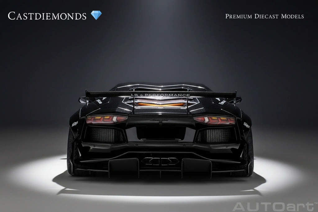 Rear view of a black diecast model sports car with a large rear wing, low profile tires, and aerodynamic design, displayed in a studio setting with a dark background.