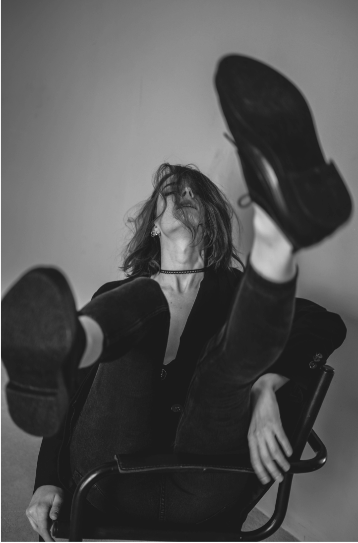 Eine Frau posiert ausgelassen mit zerzausten Haaren in einem Stuhl.