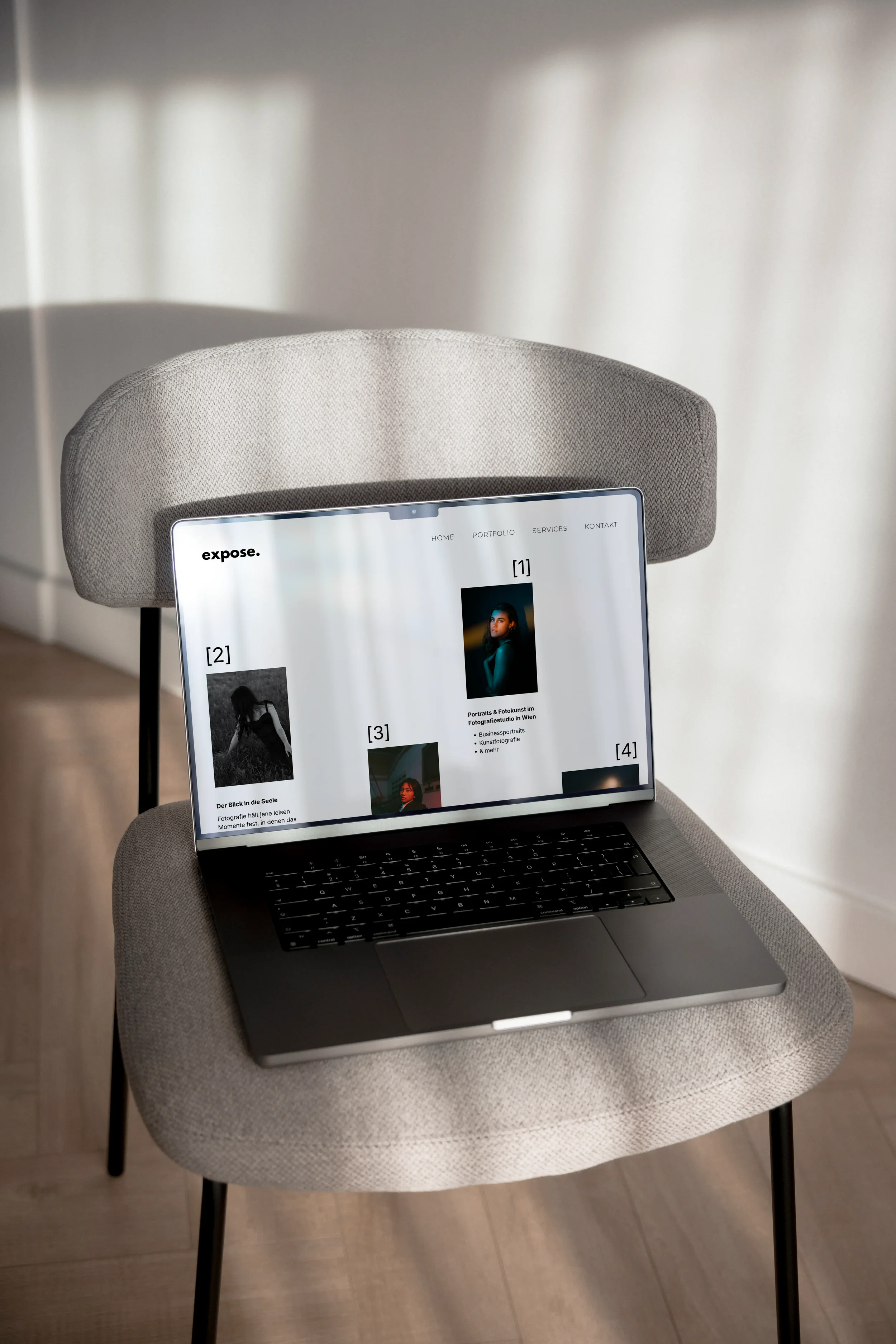 Ein Laptop auf einem grauen Stuhl, der eine Seite eines Fotografen zeigt.