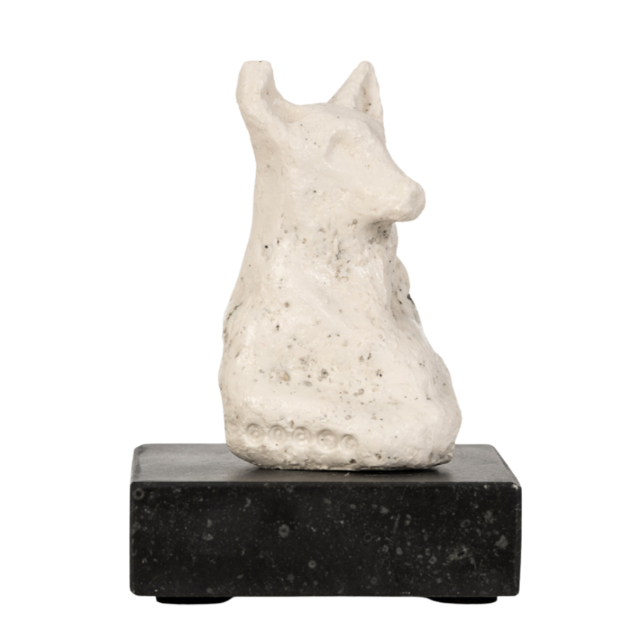 Een klein witte beeldhouwwerk van een kat of een dier met oren, geplaatst op een zwarte sokkel.