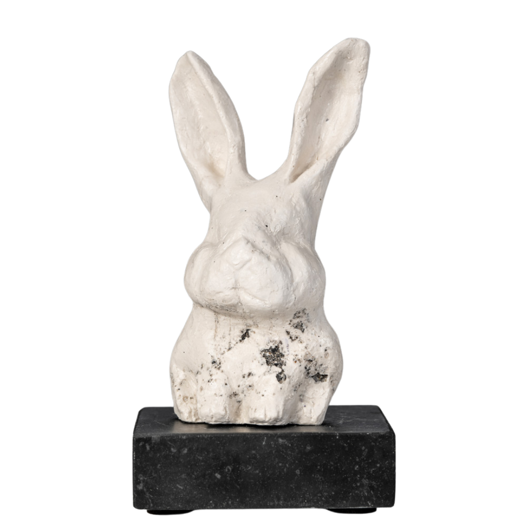 Een witte sculptuur van een konijn, geplaatst op een zwarte basis.