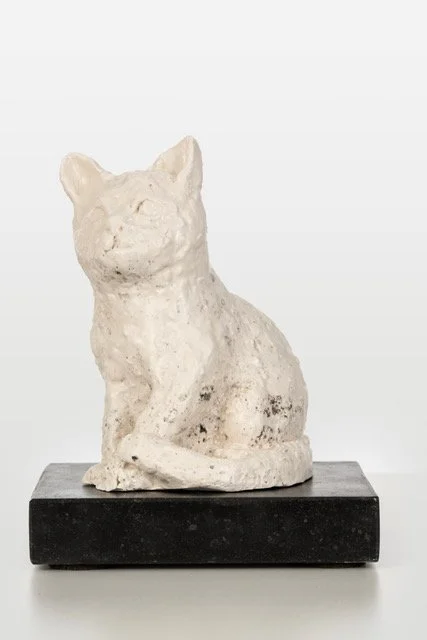 Een sculptuur van een kat gemaakt van een wit materiaal, geplaatst op een zwarte basis.