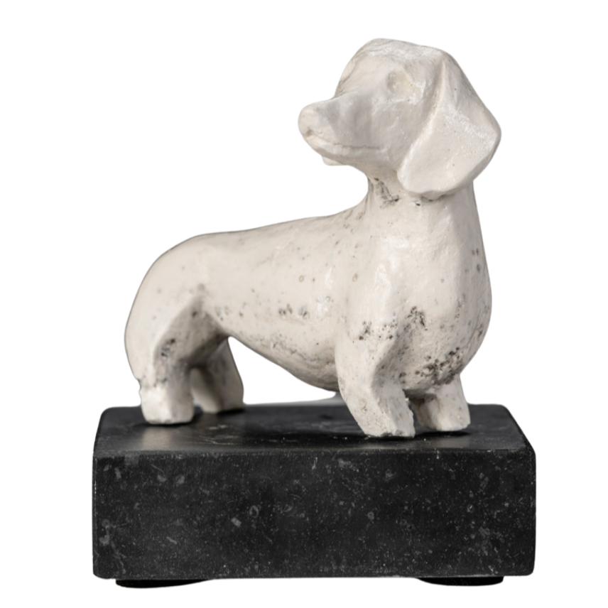 Een witte beeldhouwwerk van een hond op een zwarte sokkel.