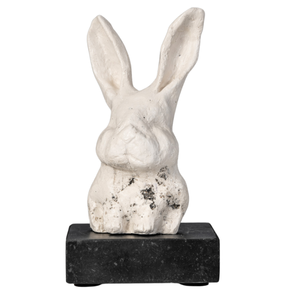 Een witte beeldhouwwerk van een konijn op een zwarte voetstuk.