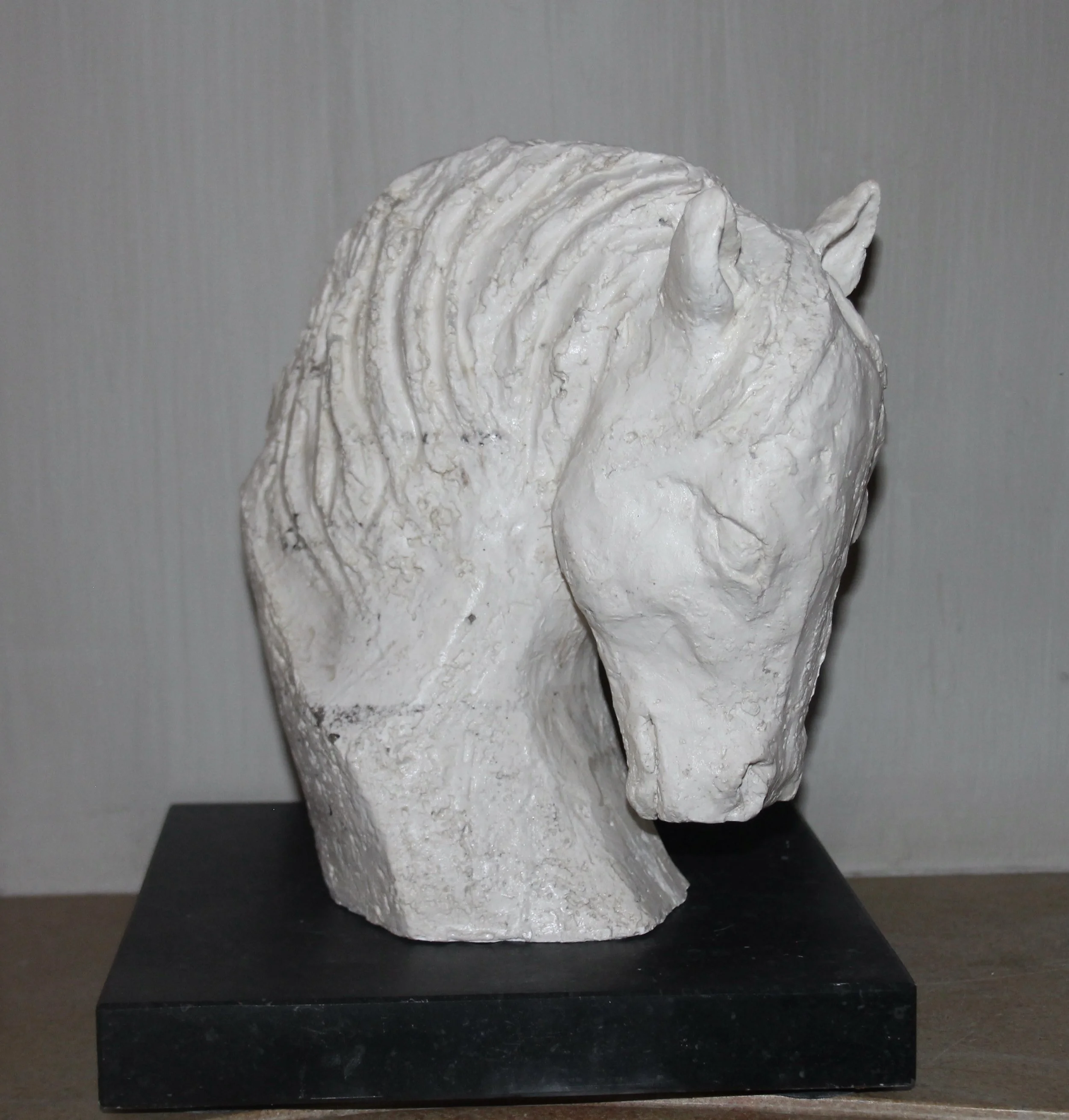 Witte sculptuur van een paardenhoofd op een zwarte voet