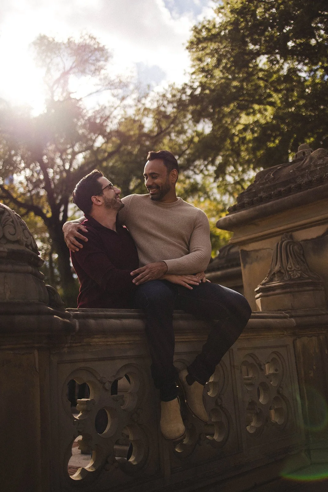 Gay couple sitting on a stone bench in Central Park during a relaxed couples photo session.
