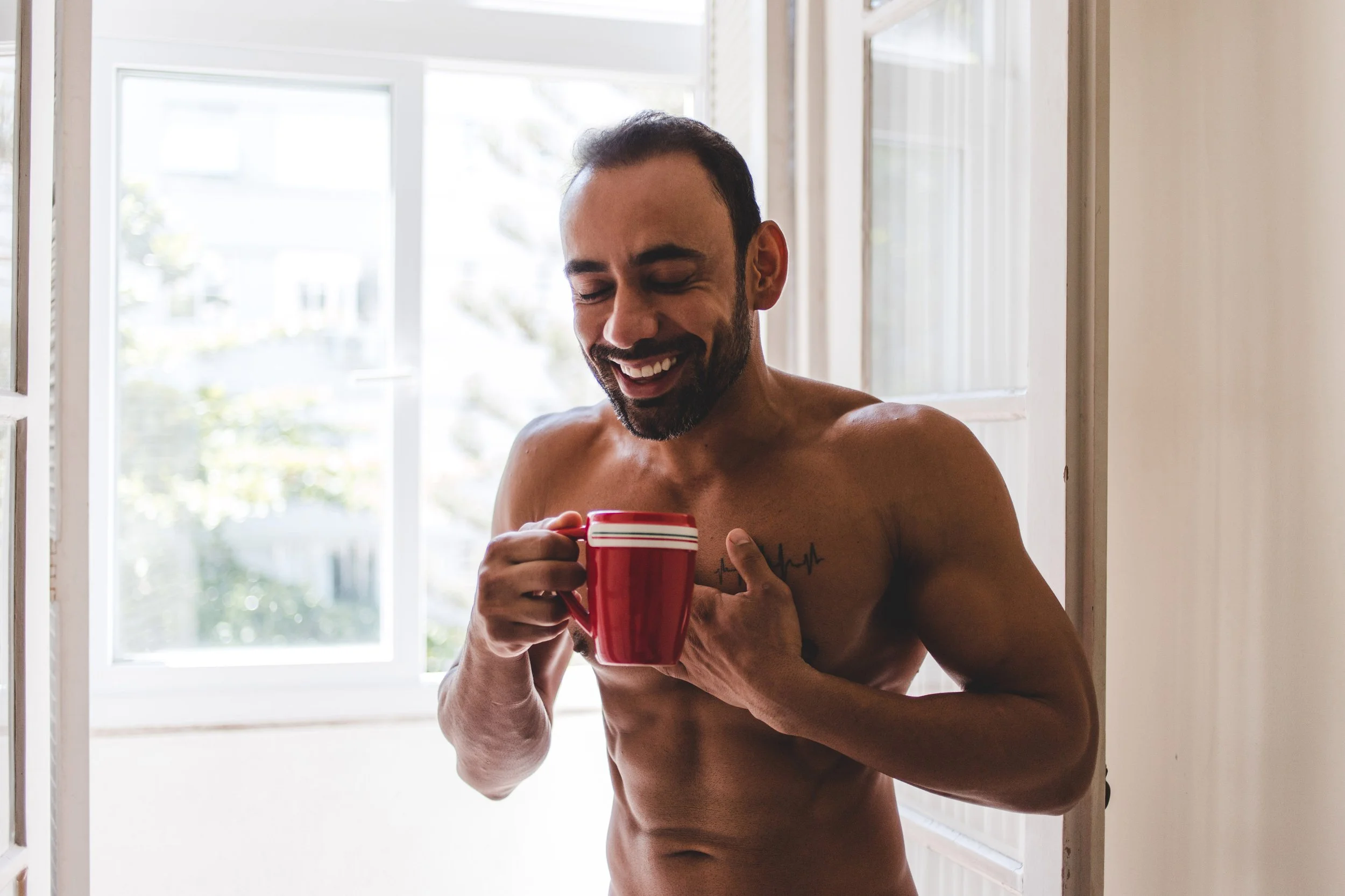 Gay male boudoir portrait photographed at home in natural light.