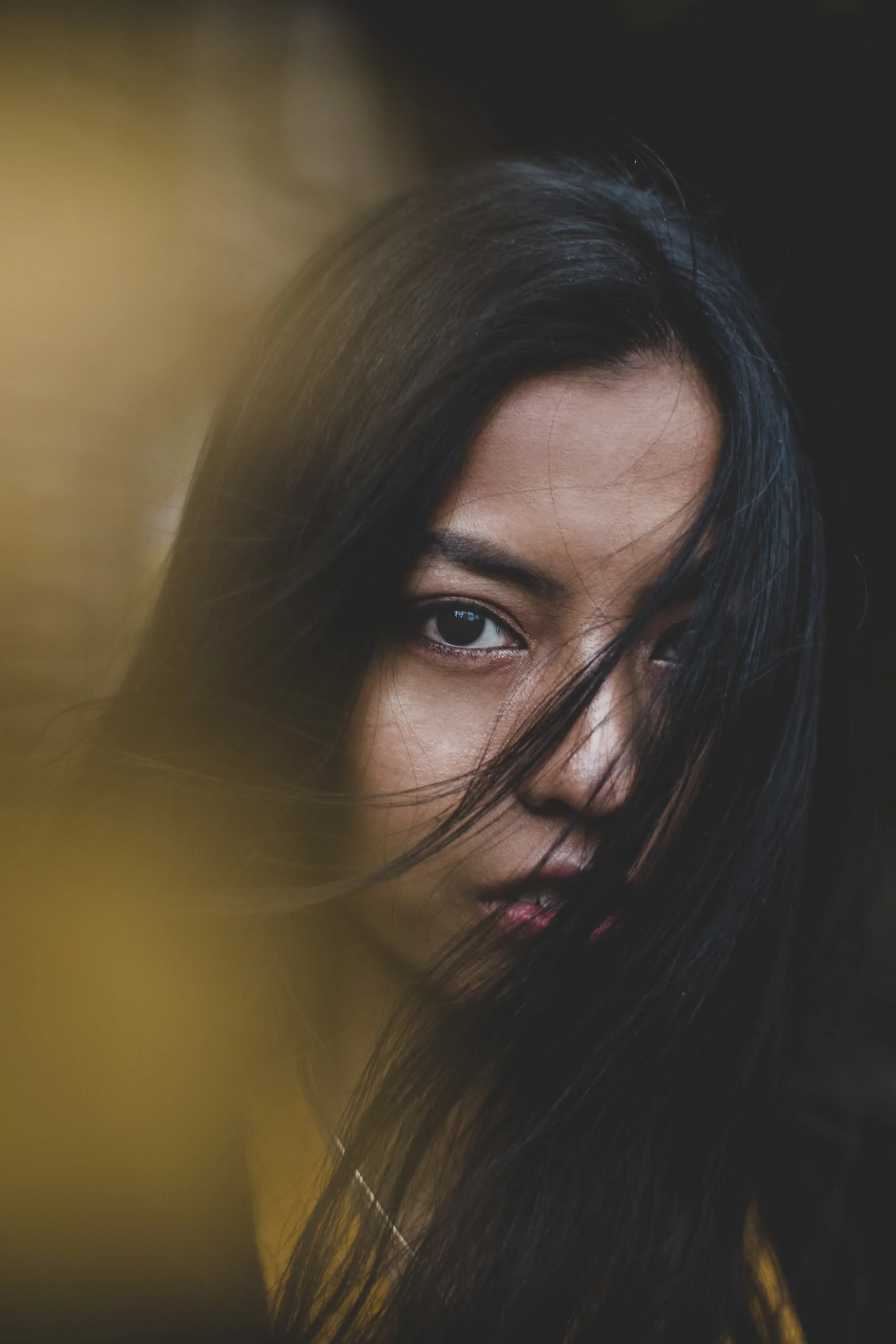 Close-up portrait of a woman partially framed by her hair during a personal portrait session.