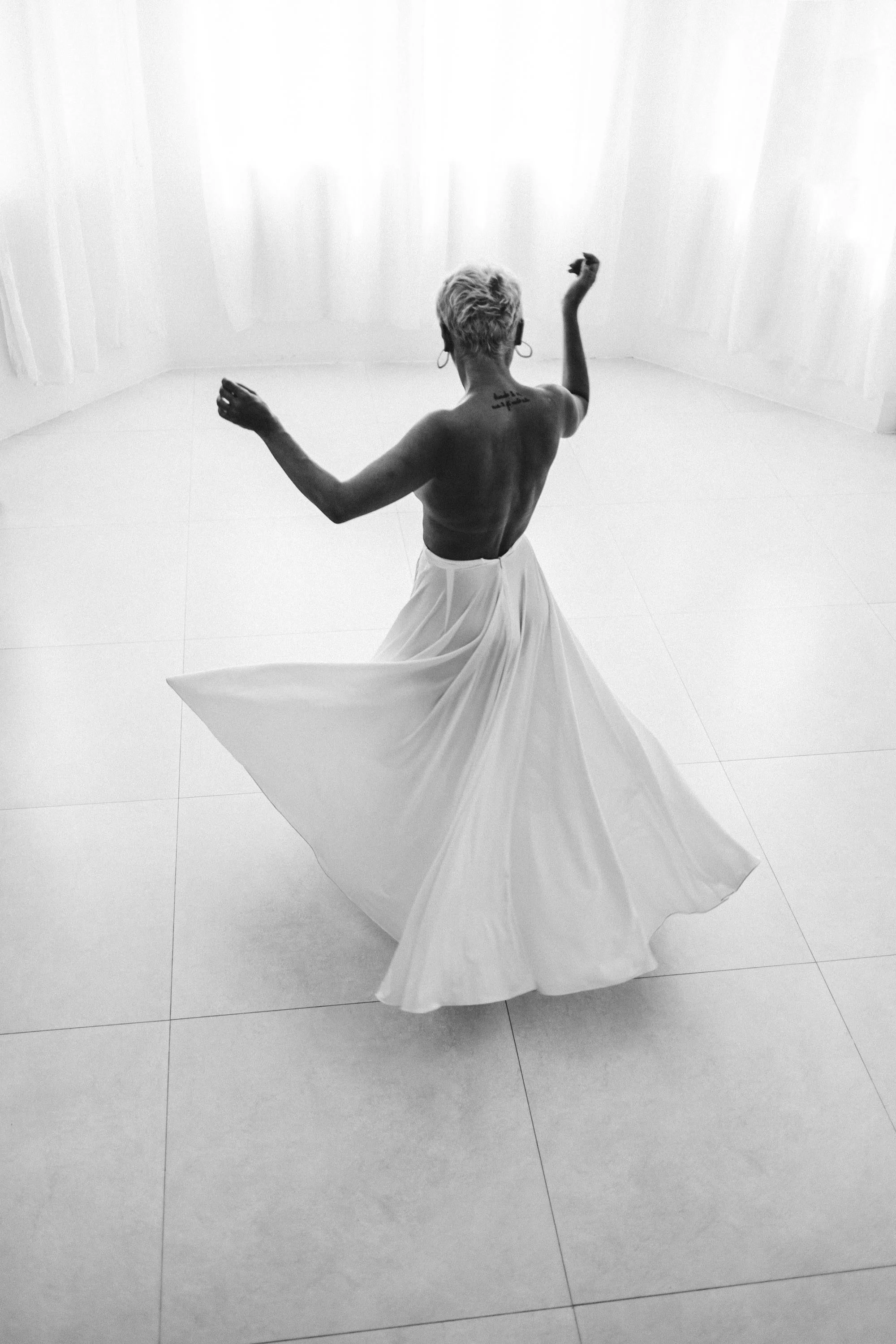 A woman spinning in a bright, minimalist space during a personal boudoir portrait session.