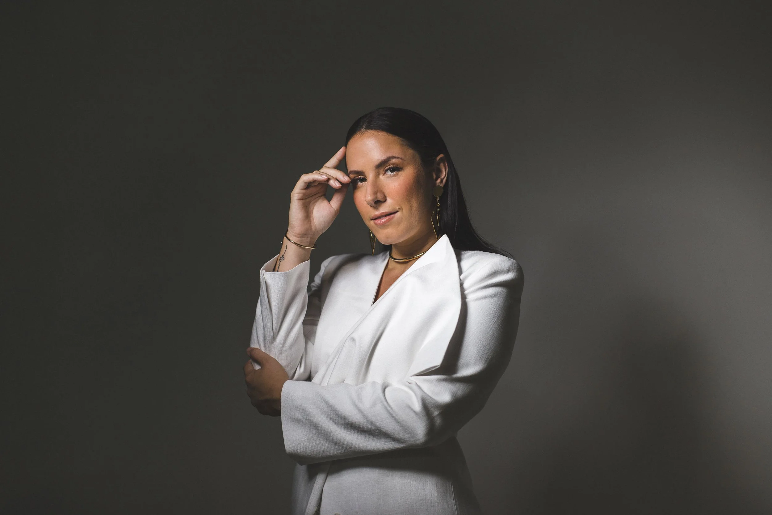 Studio portrait of a woman wearing a white blazer, photographed against a neutral background.