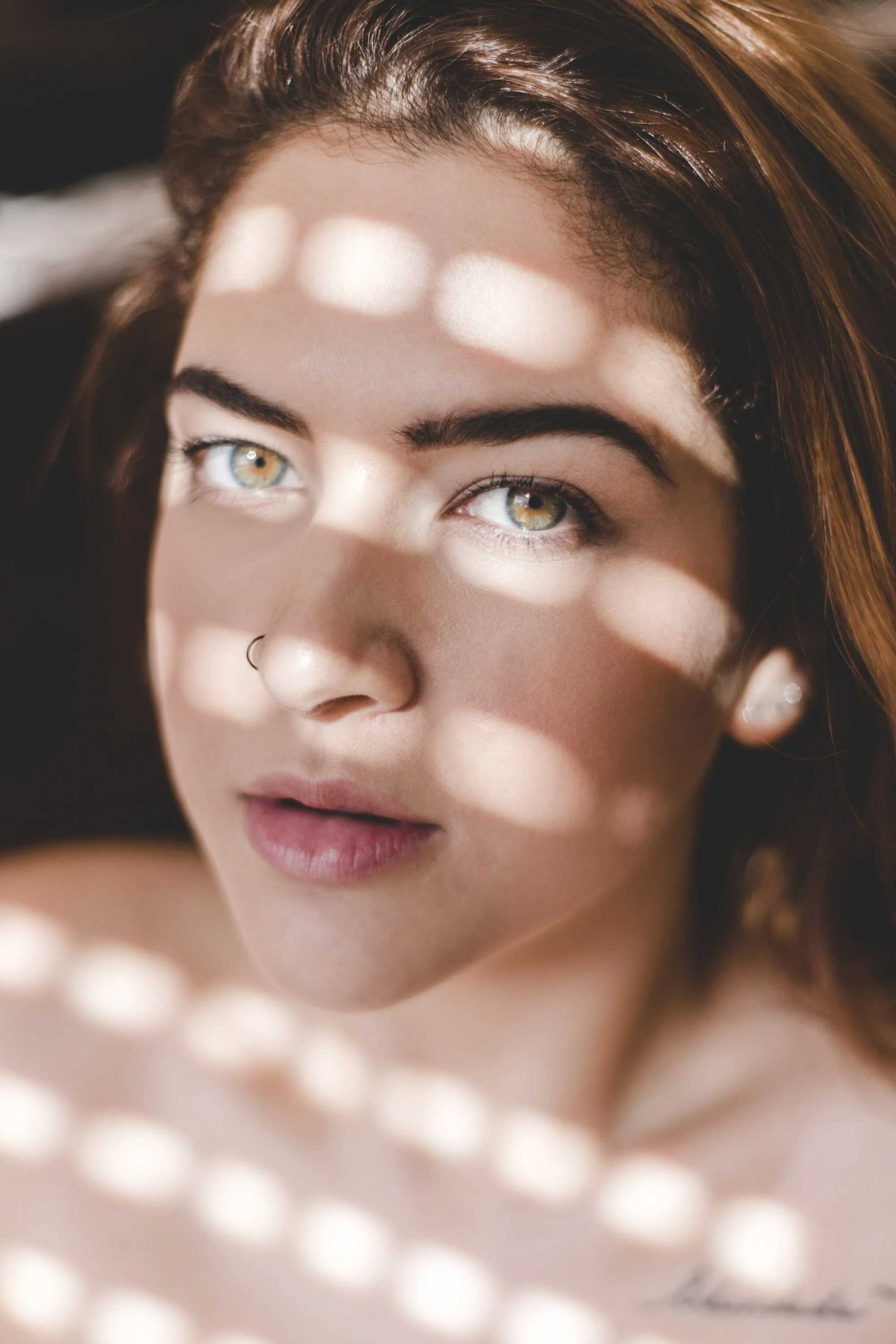 Close-up portrait of a woman in natural light during a boudoir portrait photo session.