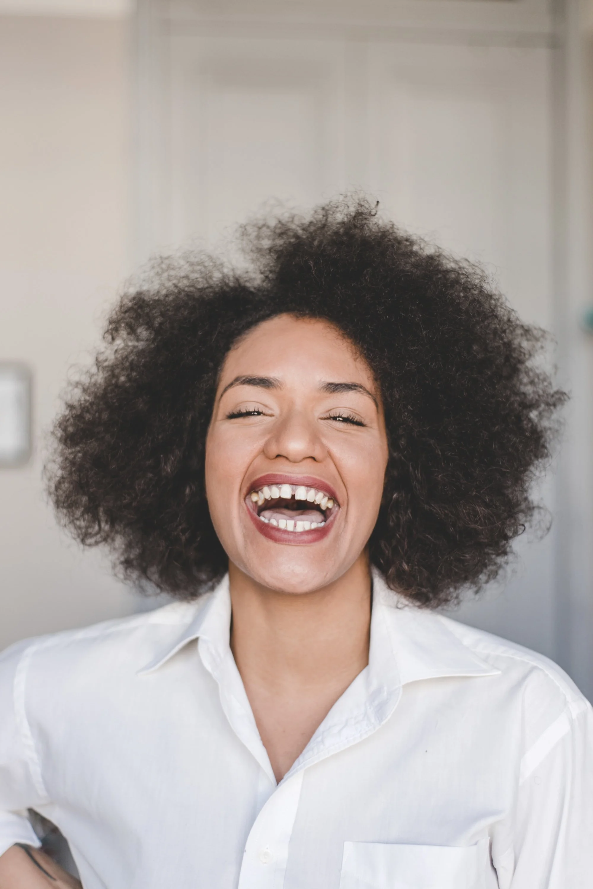 Studio portrait of Taísa Machado, creator of @afrofunkrio, laughing during a natural portrait session.