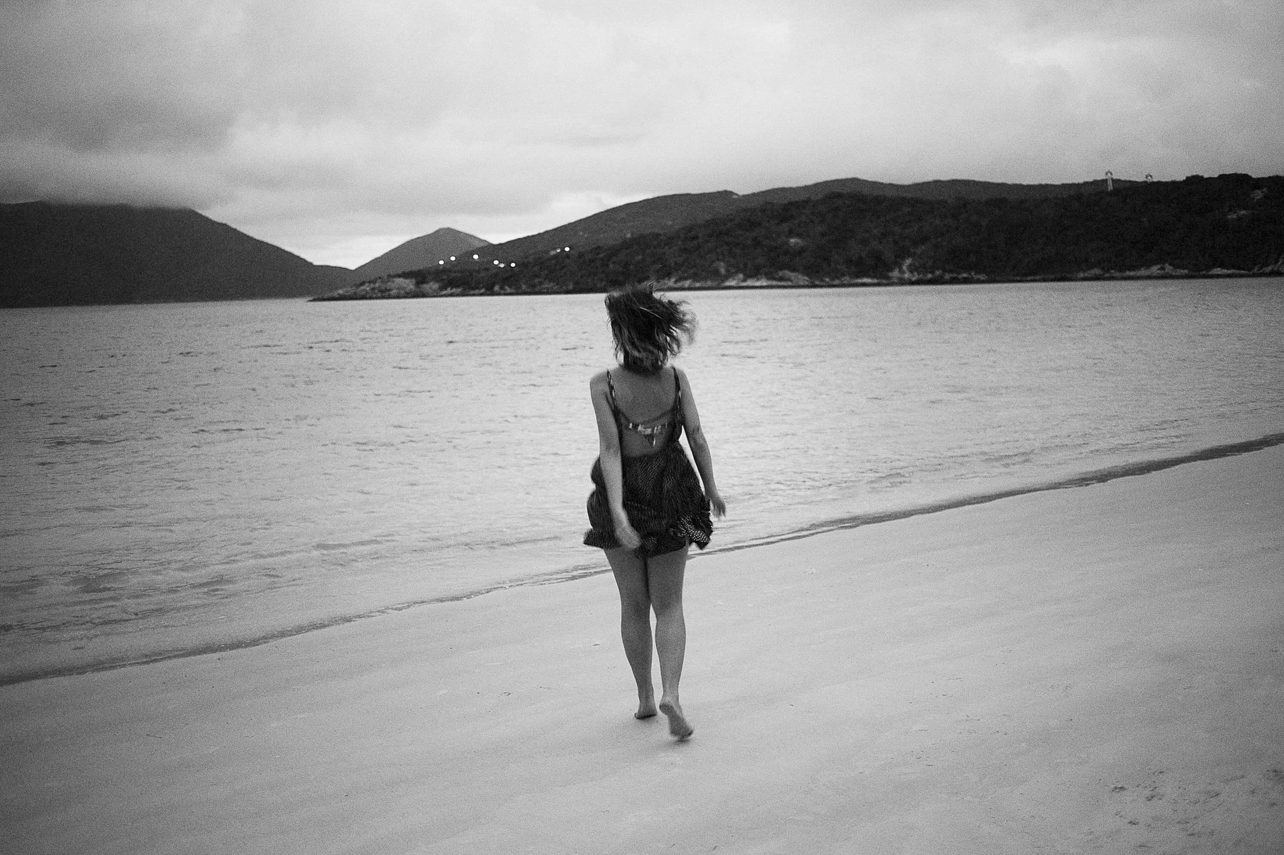 A woman running alone along the beach during a quiet portrait session in black and white.