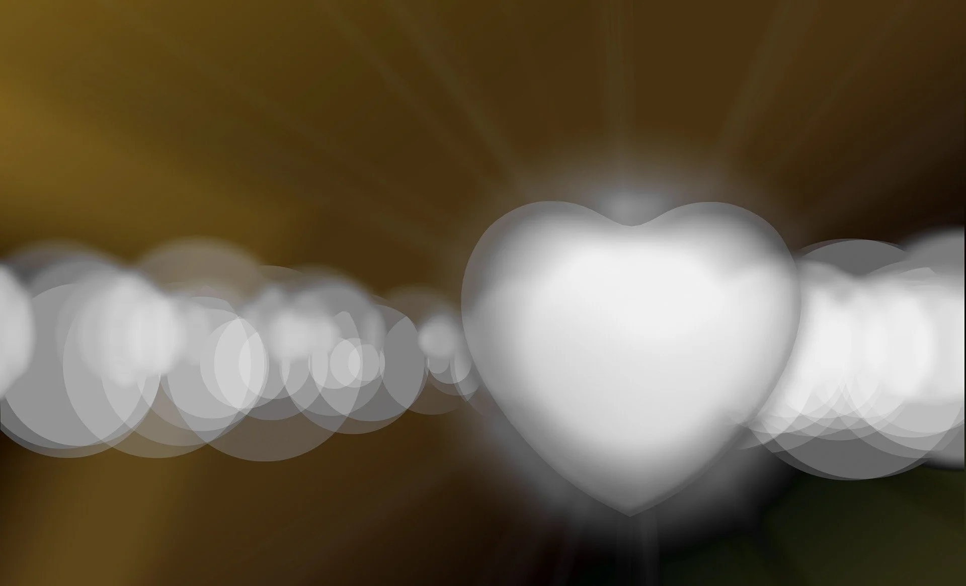 A blurred photograph of a heart-shaped object with bokeh light effects, primarily in white and brown tones.
