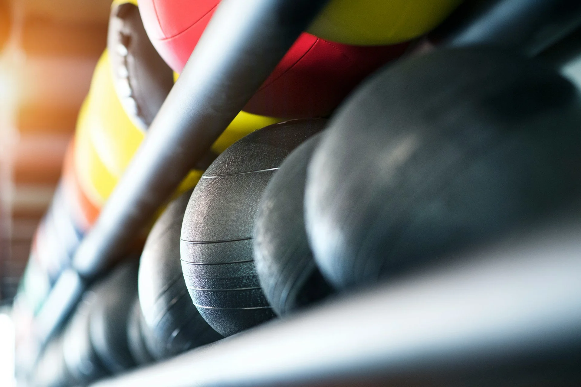 Row of kettlebells and barbells on a rack in a gym.