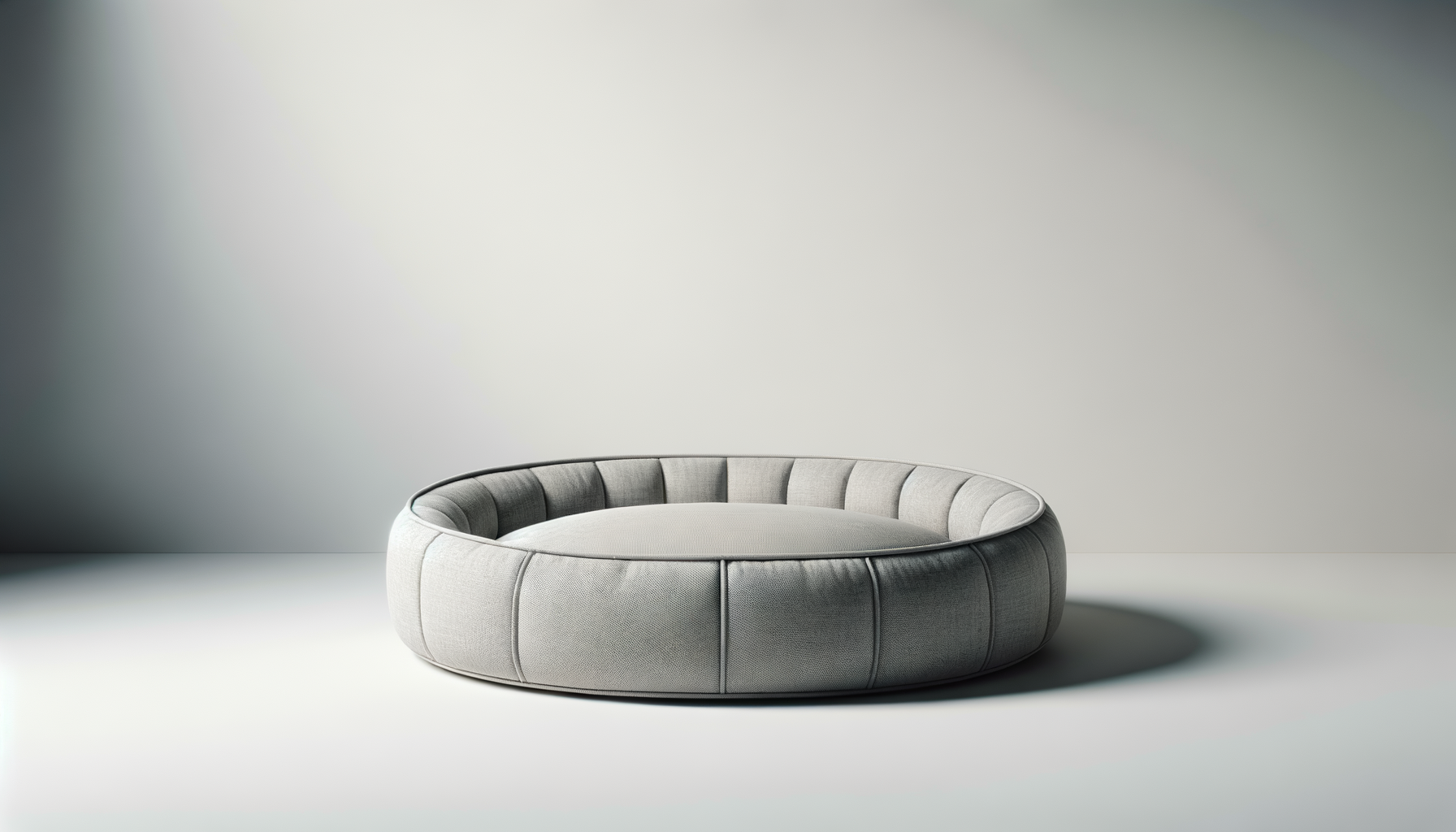 A circular gray upholstered sofa with a modern design, placed against a plain wall in a minimalist setting.