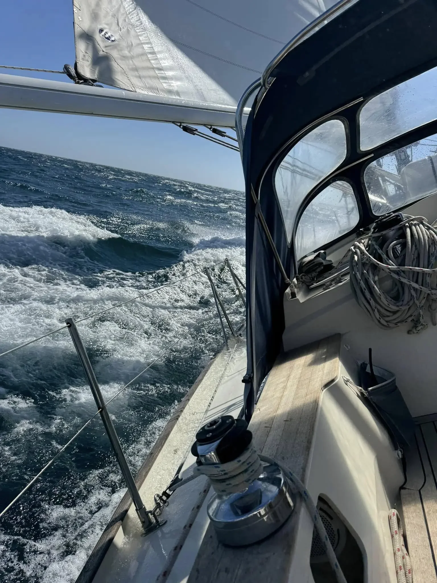 View from a yacht showing the ocean, white waves, and part of the deck