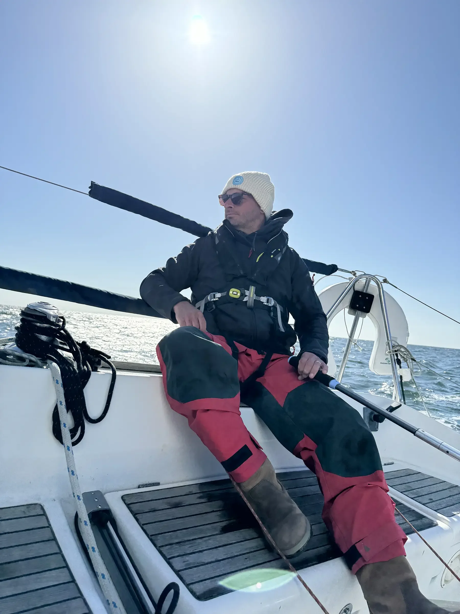 Yacht skipper sailing on the ocean on a sunny day, sitting on the side of a yacht