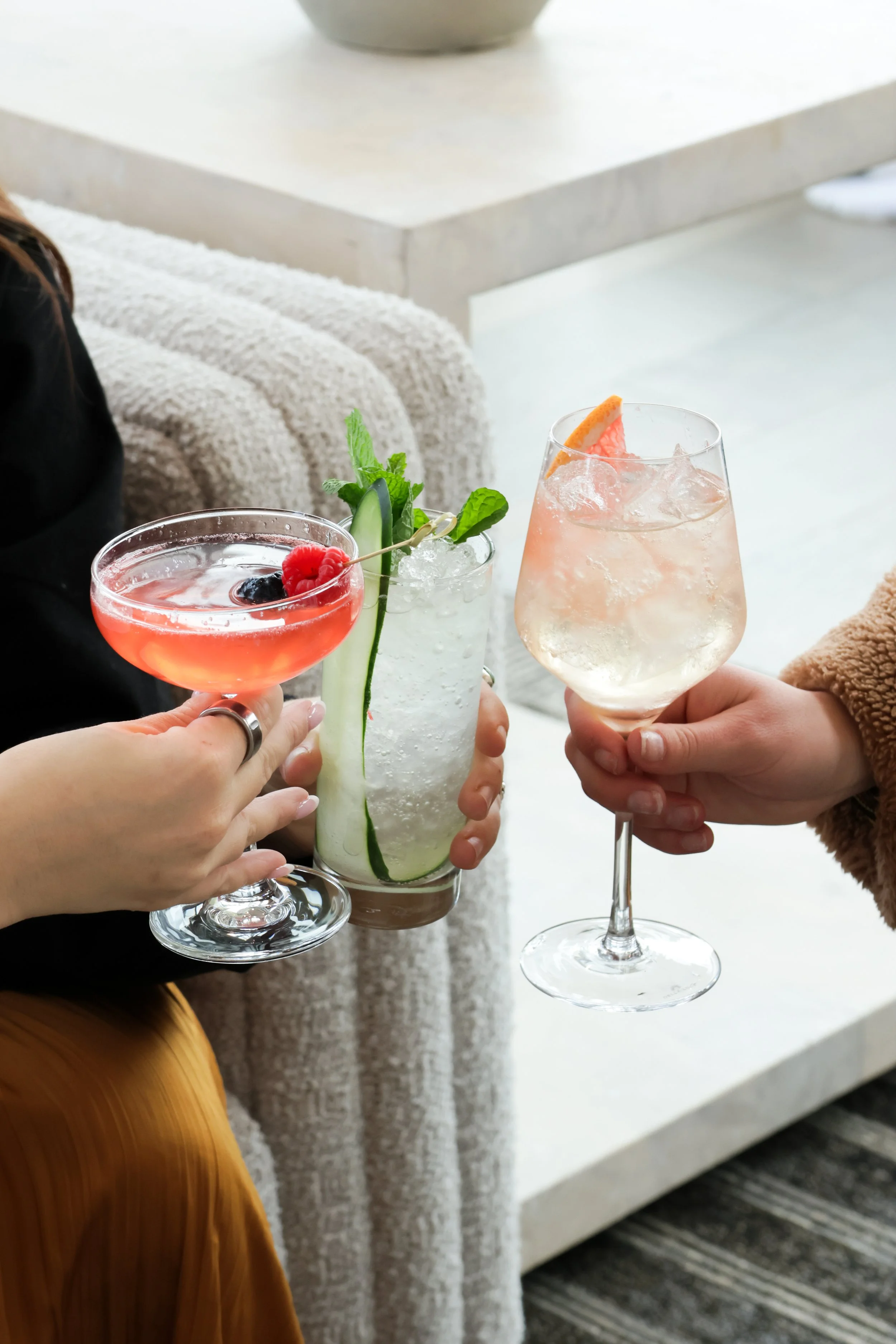 Three people holding different cocktails in a social setting.