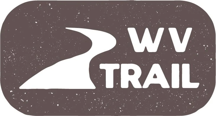 Logo for WV Trail featuring a winding trail and stylized mountain in white on a black background.