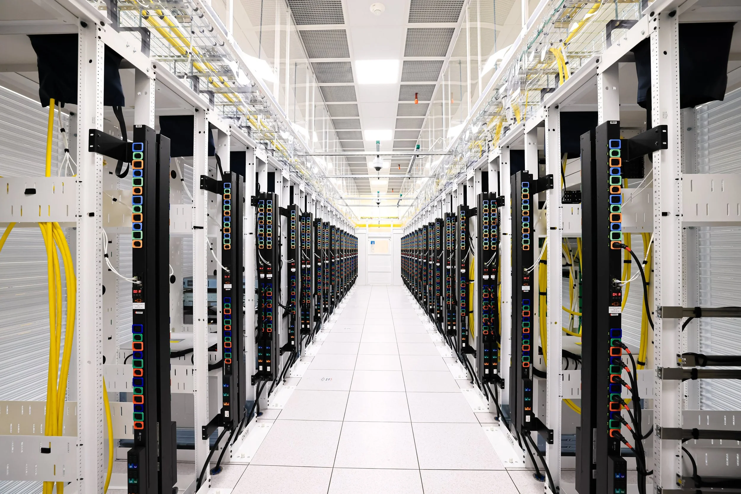 Filas de servidores en un centro de datos con cables amarillos y etiquetas en las unidades.