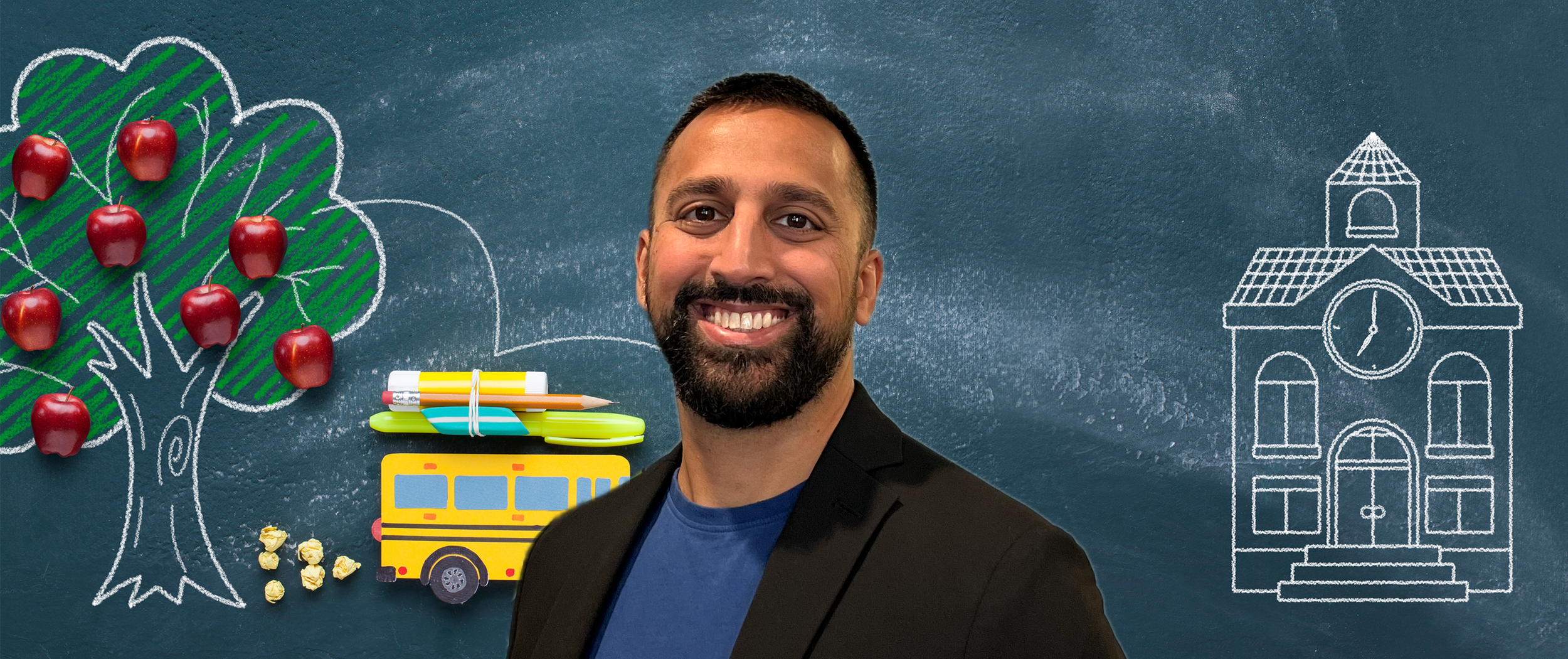 Smiling man in a black blazer standing in front of a chalkboard with a drawn school building, a chalk-drawn apple tree with decorative apples, and school supplies including a yellow school bus, pens, and popcorn.