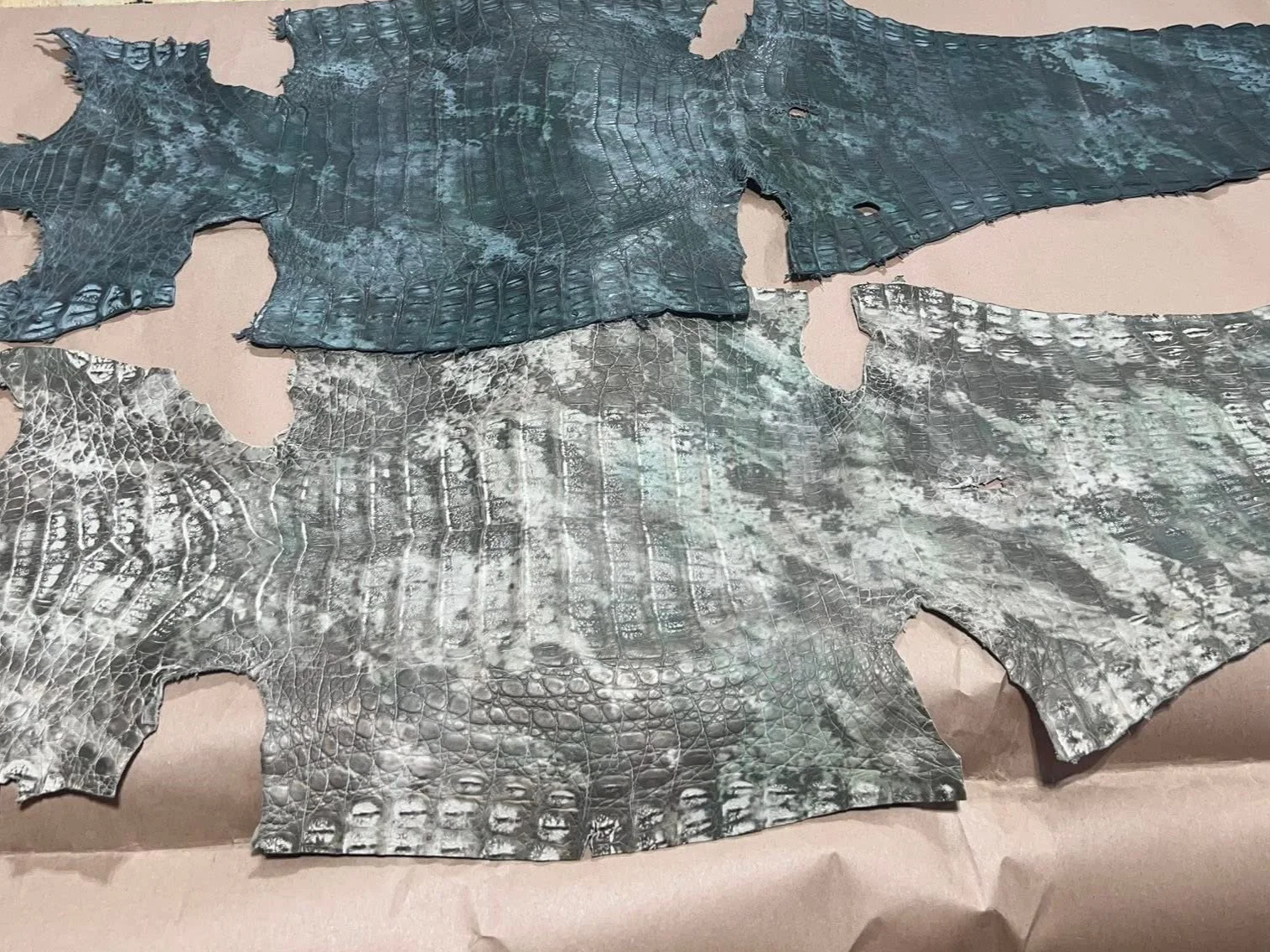 Several pieces of textured, patterned animal skin or leather, some with a scaled or reptile-like pattern, laid out on a flat surface.