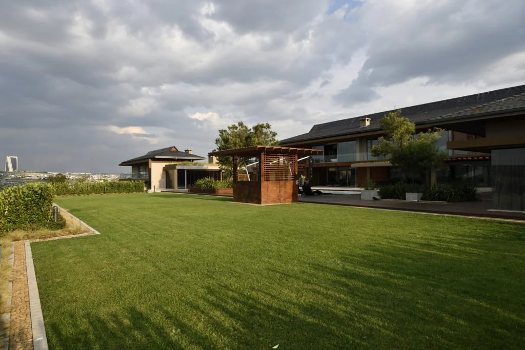 Contemporary garden with formal hedging, open lawn and swimming pool with timber gazebo