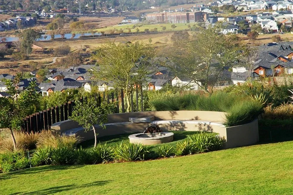 Curved sunken fire pit with seating, trees and layered planting