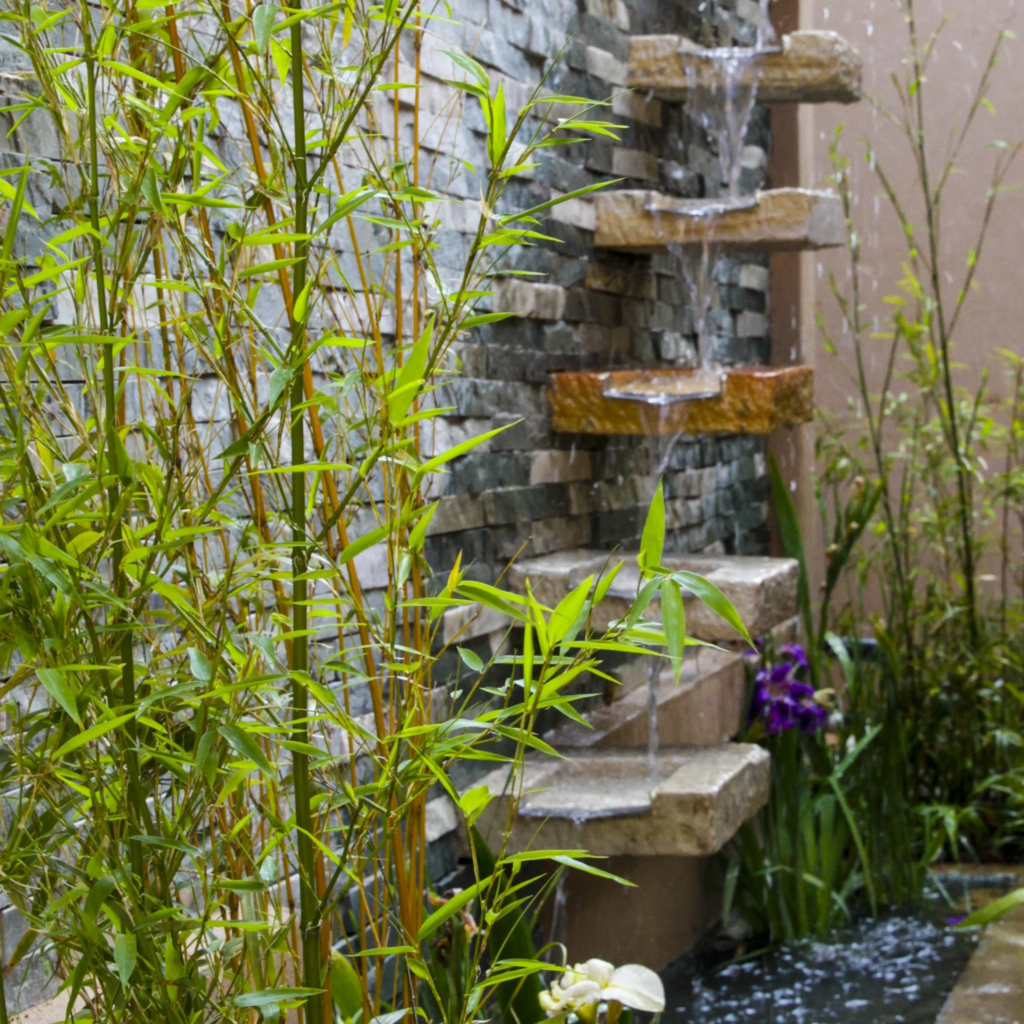 Sandstone cascading water feature with step troughs flowing into pond