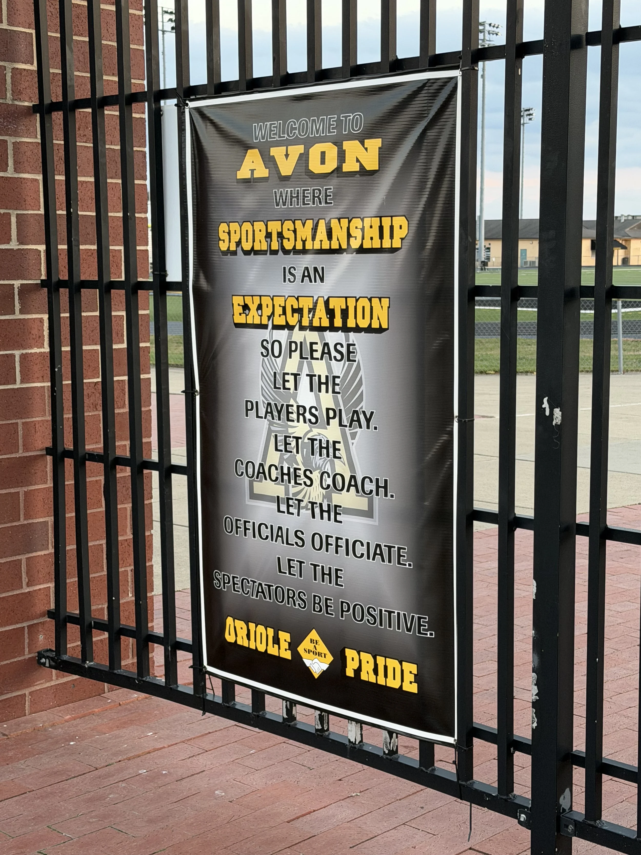 Sign on a fence with a motivational message about sportsmanship at Avon High School, featuring the school's mascot and colors.