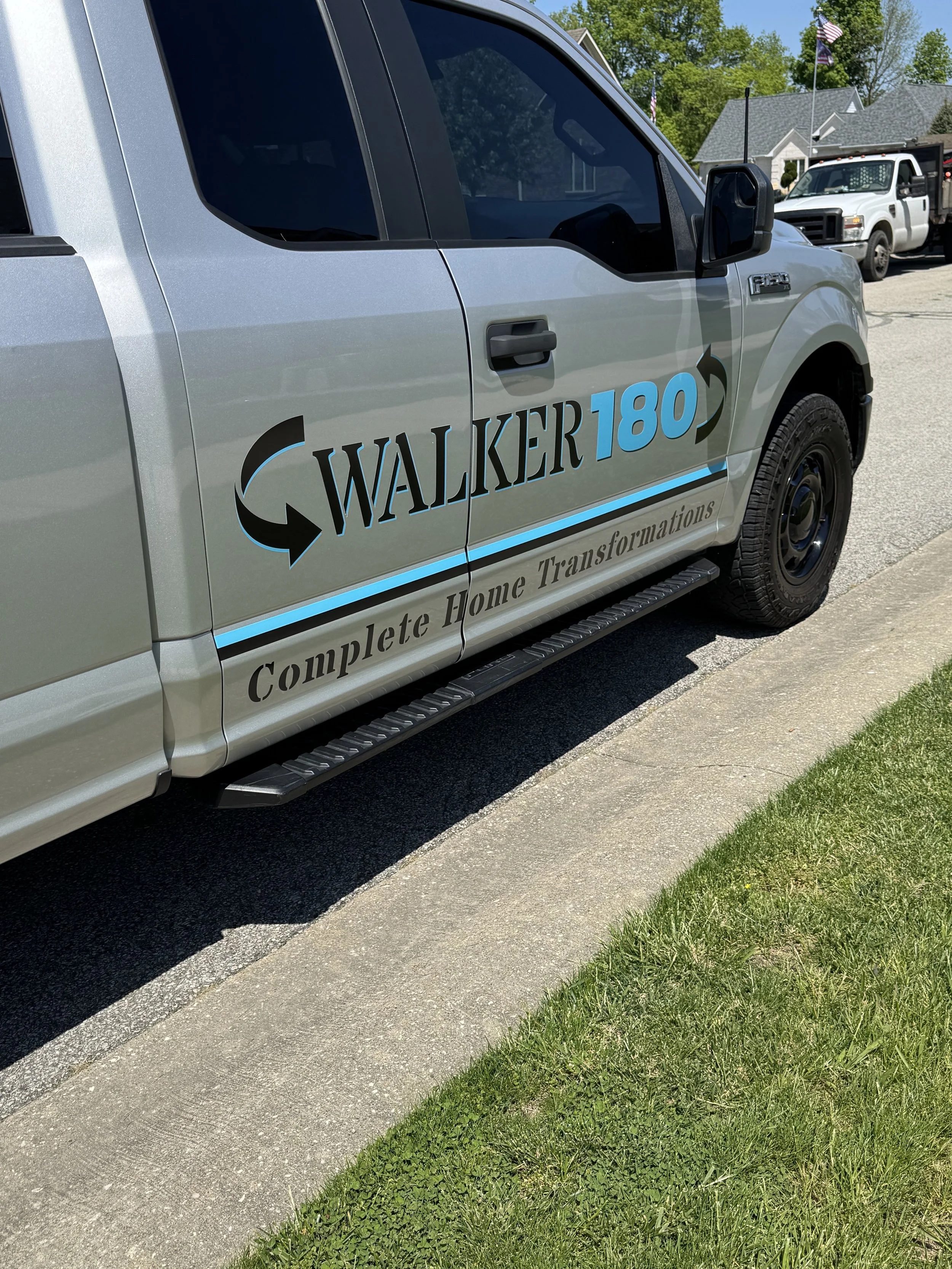 A gray pickup truck parked on the street with the company logo 'Walker180' and the tagline 'Complete Home Transformations' on its side.