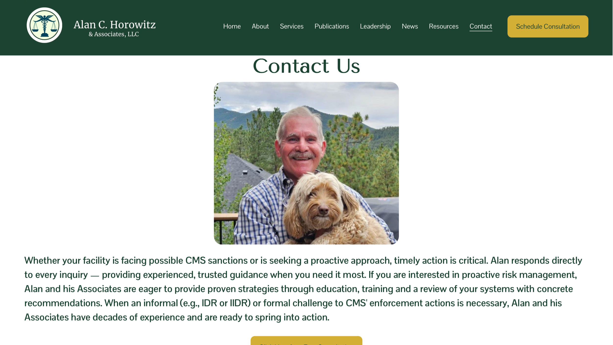 A man with white hair and a mustache smiling outdoors, holding a fluffy small dog with light brown fur, with green trees and mountains in the background.