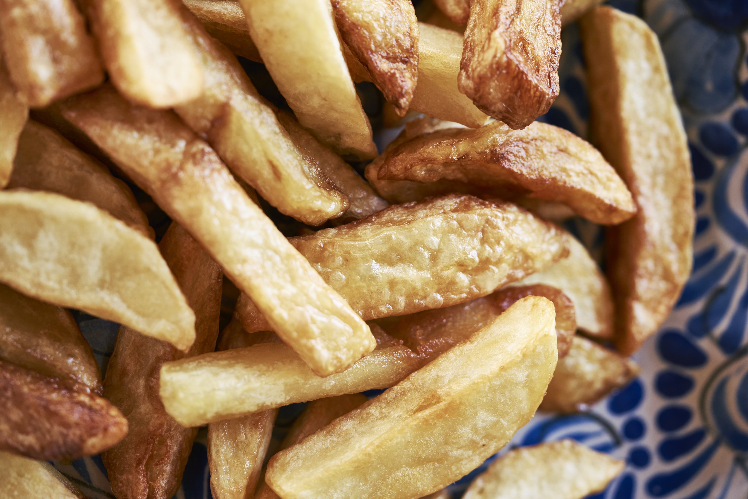 Papas fritas doradas y crujientes en un plato con diseño.