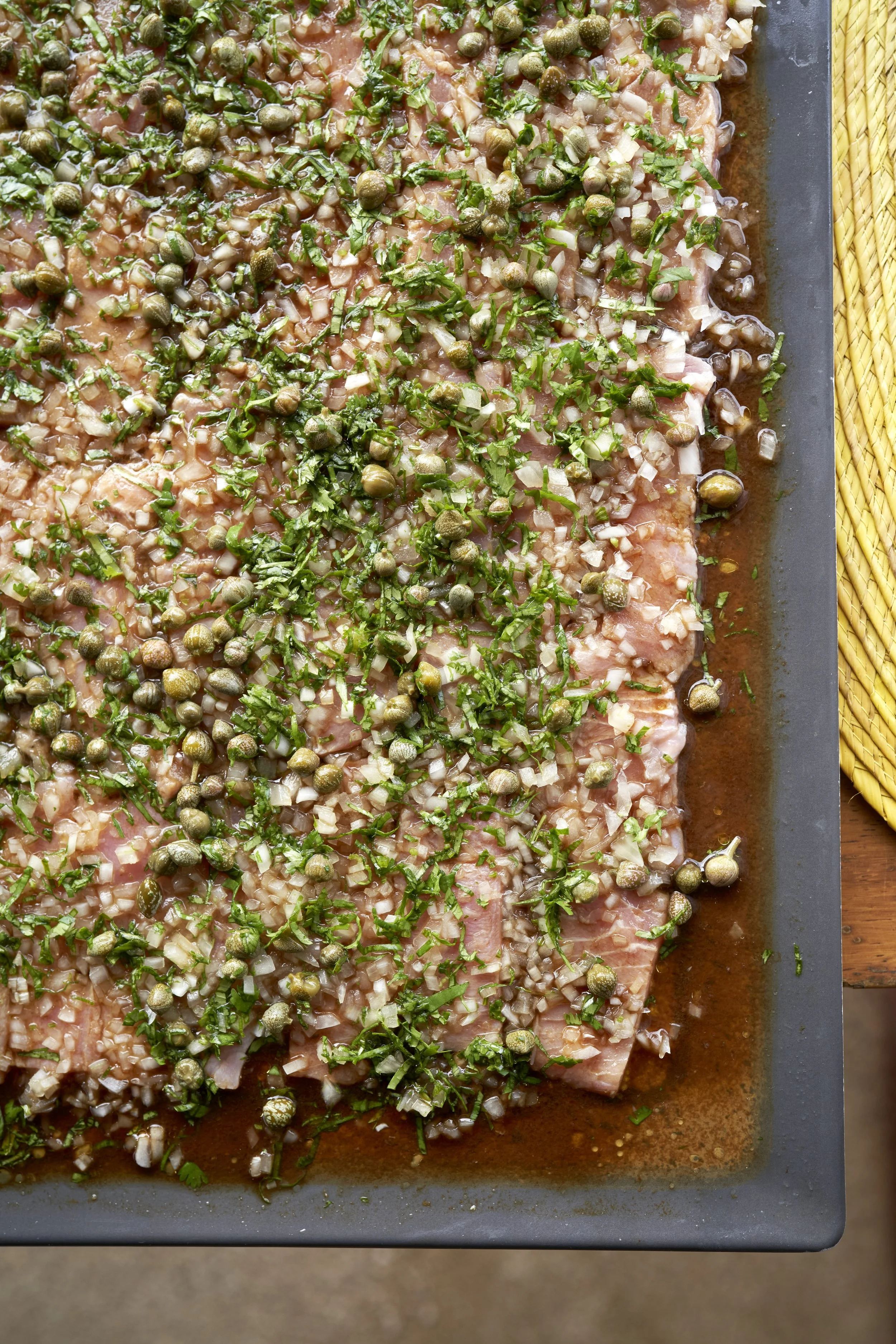 Carne de cerdo marinada con hierbas y alcaparras, lista para cocinar.