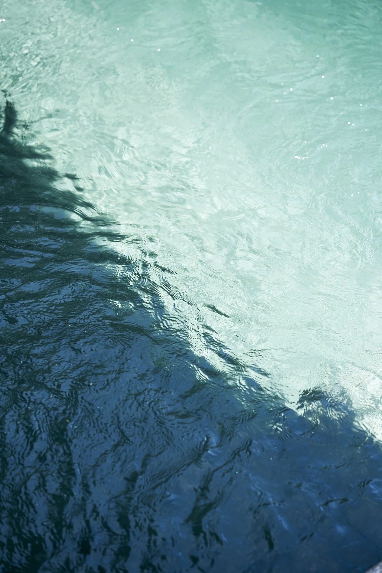 Olas en el agua con diferentes tonos de azul y verde, reflejos en la superficie.