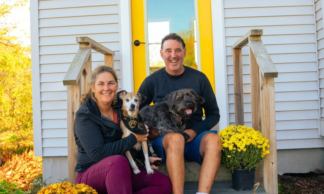 Inn owners and their dogs sitting on the  porch of their Vermont inn