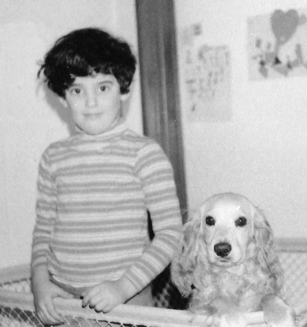 Owner at a young age standing beside his cocker spaniel.