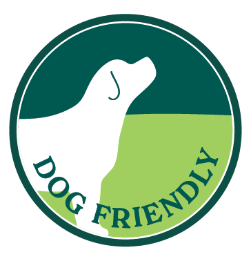 Circular logo with a silhouette of a dog's head and neck, divided into green and dark green sections, and the words 'Dog Friendly' in green text.