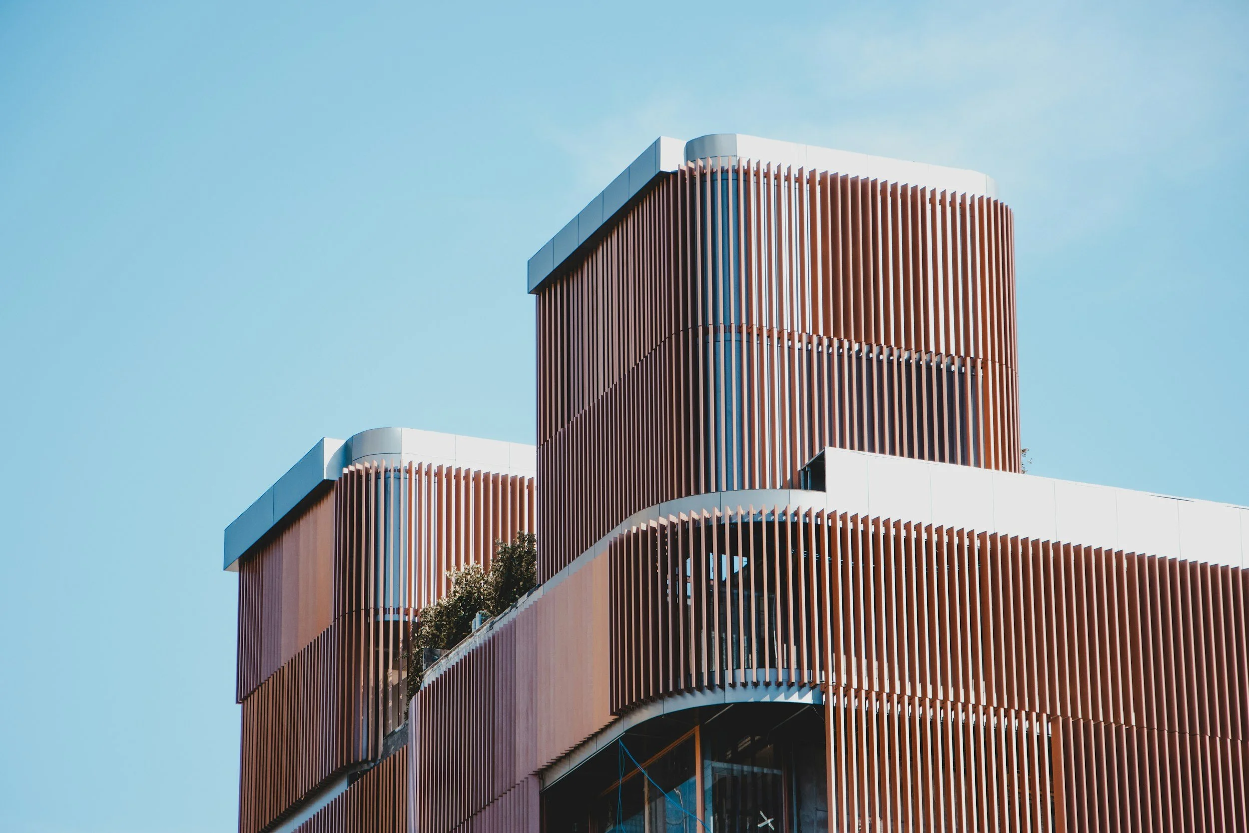 Modern building with vertical wooden slats and white accents against a clear blue sky.