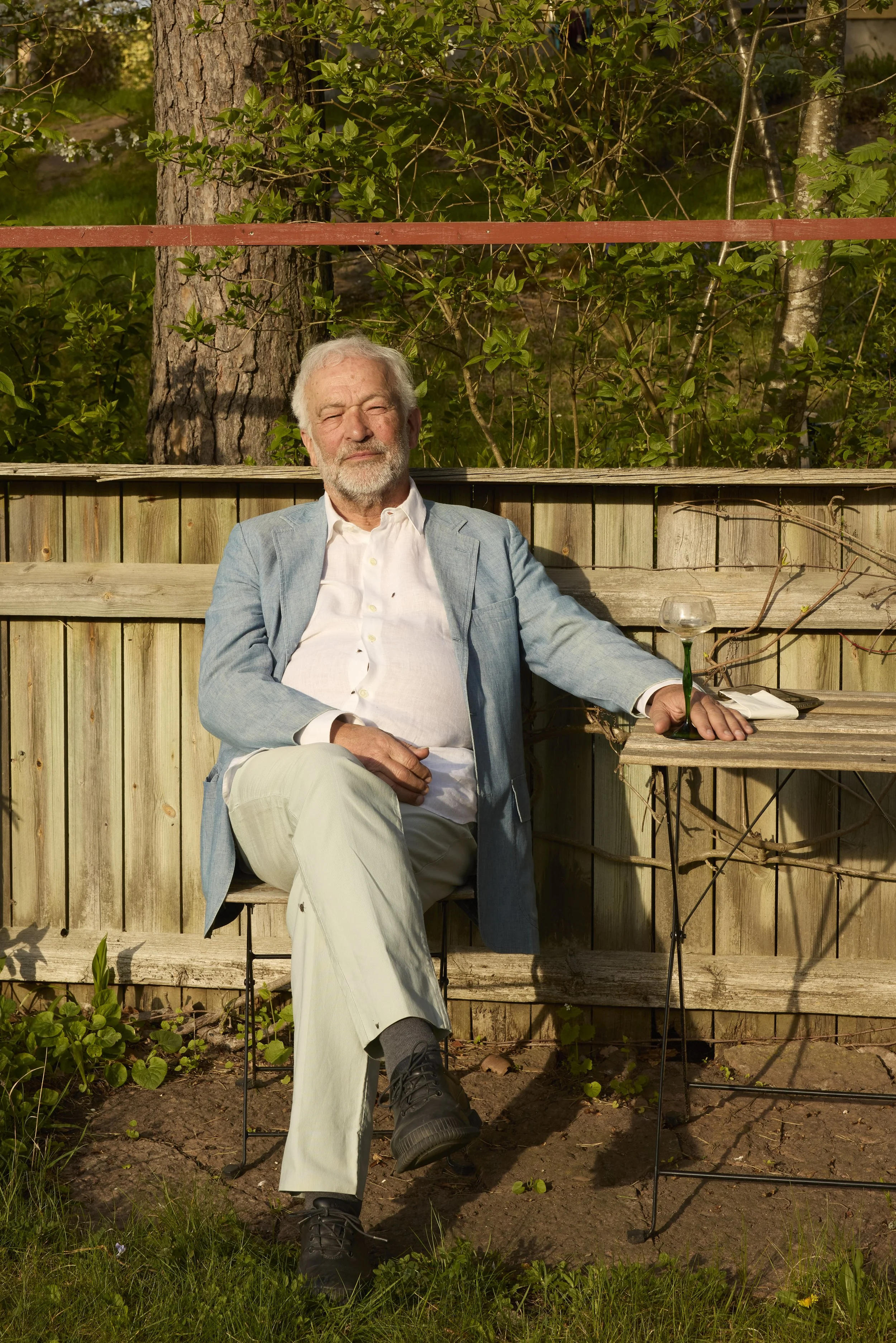 Abbi Patrix at his home in France. Green foliage and trees are in the background.