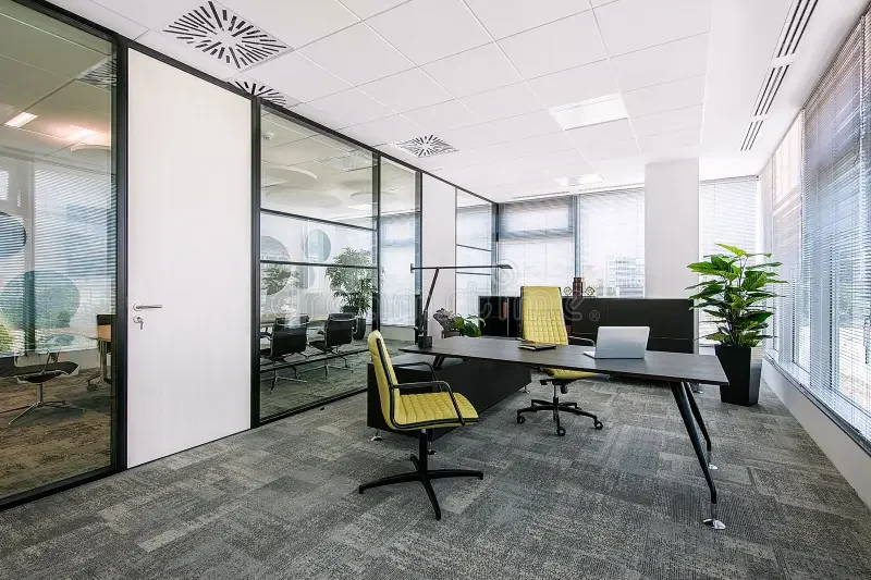 Modern office space with a desk, yellow office chair, potted plant, and large windows