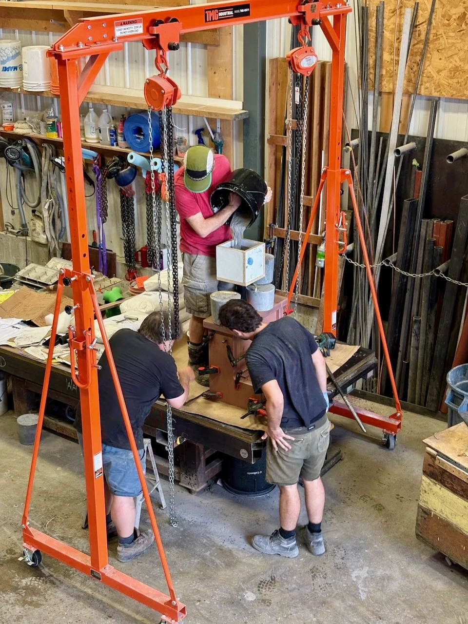 Trois personnes travaillent sur une machine dans un atelier de fabrication ou de bricolage.