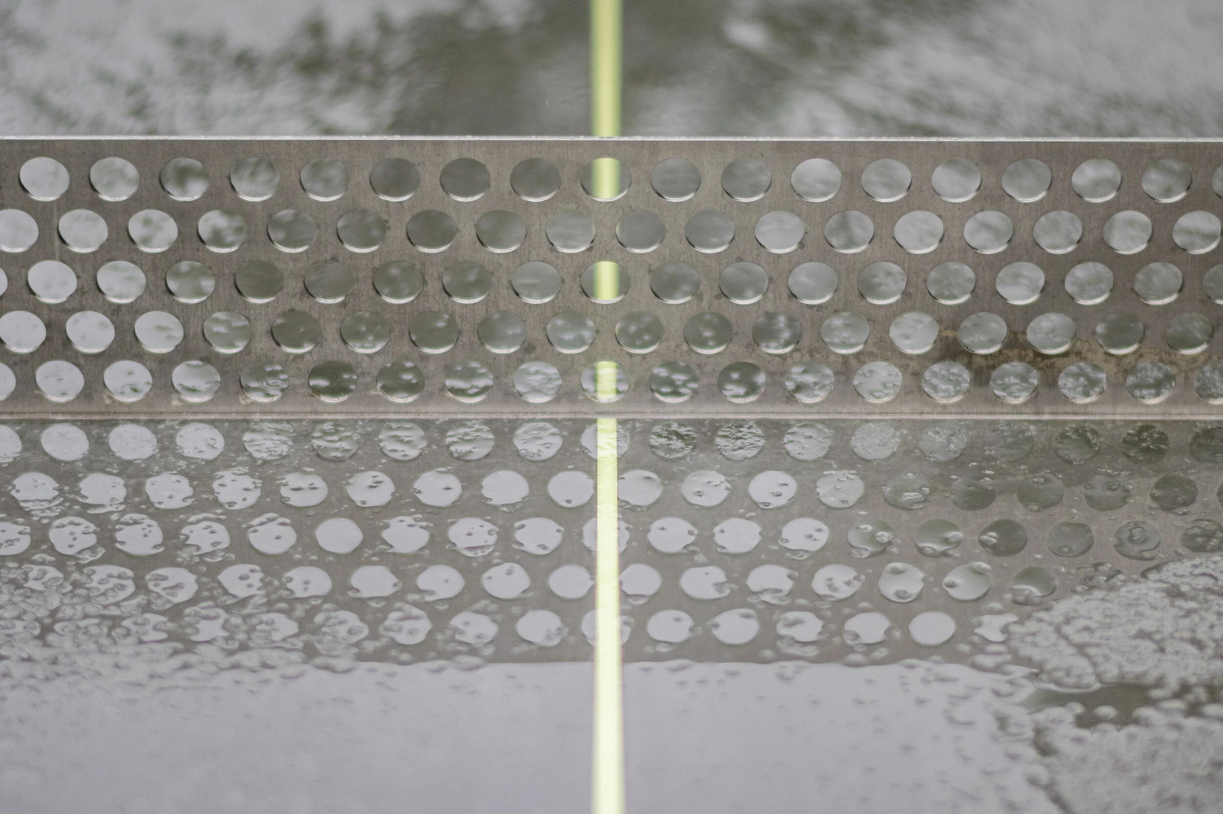 Une table de ping-pong sous la pluie, avec des gouttes d'eau sur la surface et le filet.