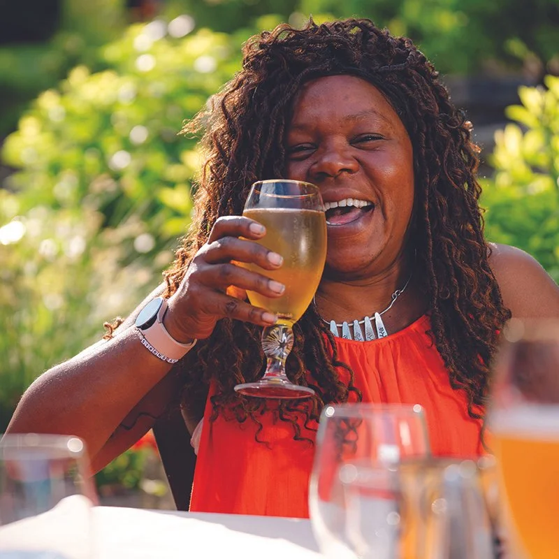 woman drinking beer from a glass outdoors on patio